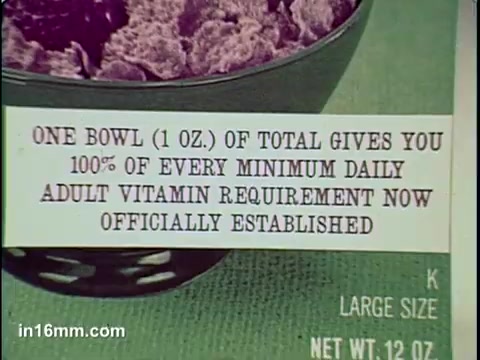 The 16mm still from the 'Total Cereal Commercial' features a close-up of a bowl filled with Total cereal, accompanied by a label that emphasizes the nutritional benefits. The text states that one bowl (1 oz.) provides 100% of every minimum daily adult vitamin requirement. The overall aesthetic of the image highlights the cereal's health-focused marketing, aiming to appeal to health-conscious consumers.