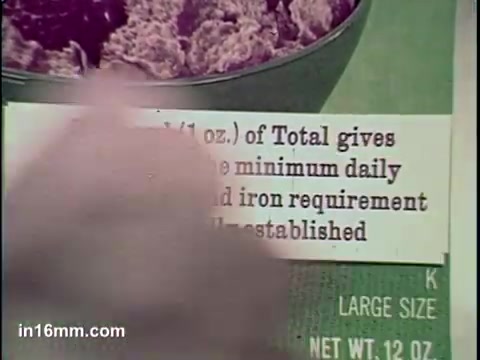 The still from the 'Total Cereal Commercial' features a close-up of a product label, highlighting nutritional information. The text mentions that an ounce of Total cereal meets daily requirements for certain vitamins and iron. The background includes a bowl of the cereal with a textured surface, emphasizing the product's appeal. The overall focus is on promoting the health benefits of Total cereal.