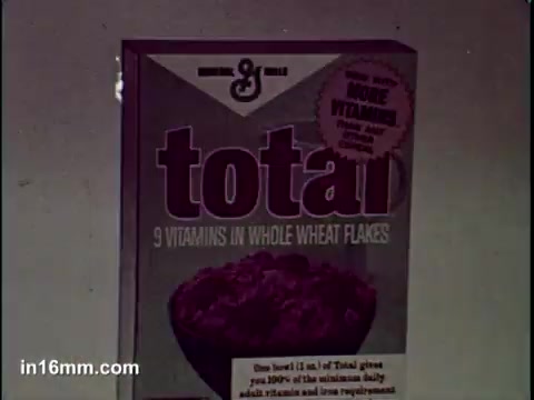 The still features a box of Total cereal, prominently displaying the brand name and key marketing points. The box highlights '9 vitamins in whole wheat flakes' and emphasizes the cereal's nutritional benefits. The design is classic, aimed at attracting health-conscious consumers.