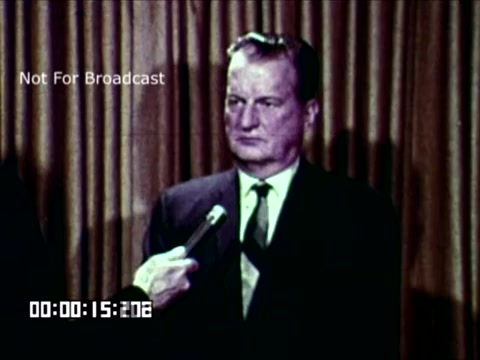 The still depicts a man in a suit being interviewed, likely discussing preferences regarding auto-color in media. He appears serious and is holding a microphone, suggesting a formal context or news segment. The backdrop features draped curtains, adding to the professional setting. The screen also includes a 'Not For Broadcast' label. Overall, it captures a moment focused on a discussion around color usage in broadcasting.