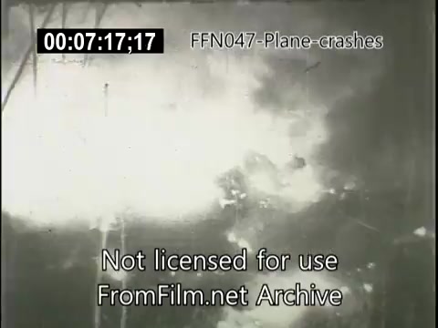 The still shows a scene from a newsreel depicting a plane crash. The image captures a chaotic and smoky environment, indicating the aftermath of the incident. Flames and debris are likely present, suggesting significant destruction. The footage is part of an archival collection labeled 'FFN047-Plane-crashes.'