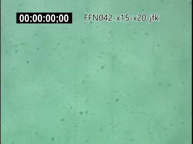 The still shows a blurred, greenish background, possibly representing either atmospheric or underwater footage. It includes a timestamp reading '00:00:00;00' and a labeled title 'FFN042-x15-x20-jfk'. This suggests it is part of archival footage related to the X-15 and X-20 Dynasoar programs and possibly linked to JFK's involvement in aerospace initiatives. The overall visual quality indicates it is a frame from a 16mm film.