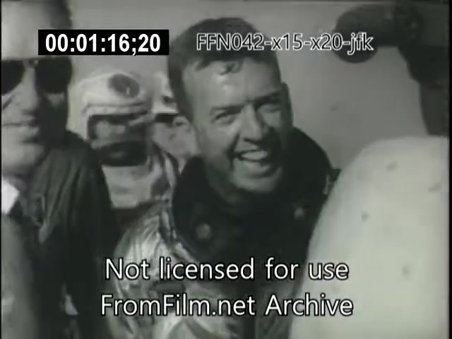 The still from the footage shows a group of people, including a man in a flight suit, smiling and engaging positively with others. The context suggests a significant moment related to the X-15 or X-20 Dynasoar programs, possibly in relation to their achievements or a public appearance. The image captures a moment of camaraderie and achievement in the early era of aerospace exploration.