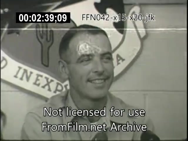 The still features a man smiling as he speaks, likely in an interview setting. He is in front of a wall displaying an emblem, possibly related to aviation or space exploration, indicating a context of flight testing or achievements. The timestamp and watermark suggest the footage is from an archival source. The overall atmosphere appears to capture a moment of confidence and pride in relation to significant aerospace programs.