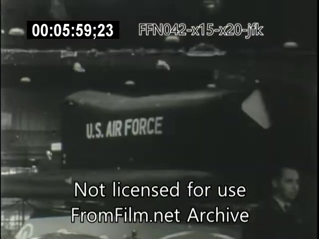 The still features a U.S. Air Force aircraft in a hangar, likely related to the X-15 or X-20 Dynasoar programs. The setting appears to be a historical exhibition or event, with aircraft and personnel visible in the background. The footage indicates a focus on early aerospace technology, reflecting the era's innovation and connection to significant figures like JFK. The timestamp suggests it is from a film archive documenting these historical events.