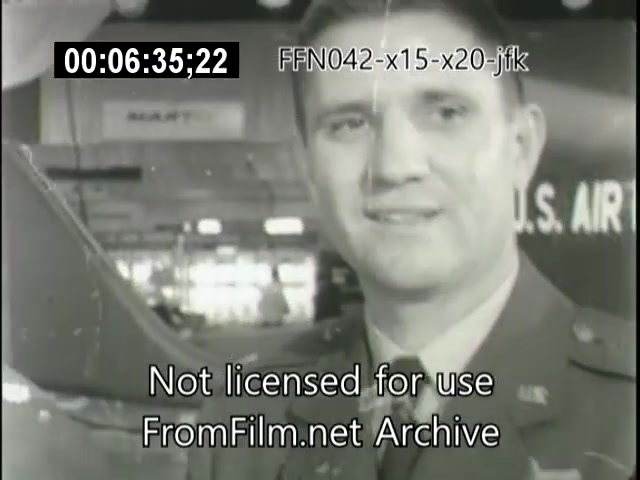 The still features a man in a military uniform, likely an Air Force officer, smiling while standing in front of an aircraft model. The background suggests a showcase or exhibition, with signs indicating 'U.S. AIR FORCE.' The footage appears to be part of a historical presentation related to the X-15 and X-20 Dynasoar programs, with a timestamp and archival markings visible.