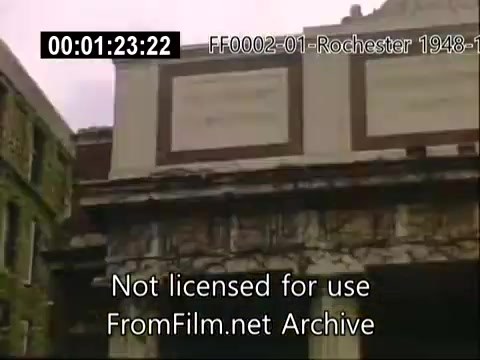 The still shows a historic building at the University of Rochester, likely part of the School of Medicine, captured in Kodachrome film from the late 1940s to 1950. The architecture features ornate details, typical of the era, with a focus on the façade and inscriptions. The scene conveys a sense of academic heritage and the ambiance of the university during that period. The footage is part of archival home movies, showcasing life and landmarks around the university.