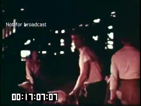 The still from the educational film 'Immigrant Heritage' featuring the Irish Rovers depicts a scene likely set in an industrial or workshop environment. Men are shown engaged in manual labor, highlighted by the warm tones typical of 16mm film. The atmosphere suggests a focus on the immigrant experience and the hard work associated with building a new life in a different country. The text 'Not for broadcast' indicates it's not intended for public viewing, and the timestamp suggests a specific point in the film's runtime.