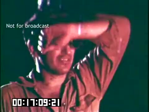 The still from 'Immigrant Heritage' features a man wiping sweat or shielding his eyes, suggesting a moment of exhaustion or distress. He appears to be in a warm or challenging environment, likely in a context that explores themes related to labor or immigrant experiences. The 16mm format conveys a vintage aesthetic synonymous with educational films of the time.