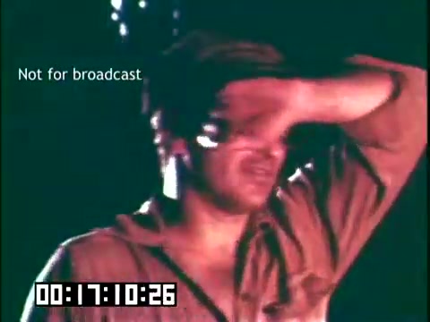 The still from 'Immigrant Heritage' features a man with his arm raised against his forehead, possibly shielding his eyes from light. He appears to be in a contemplative or stressed state. The lighting creates a dramatic effect, emphasizing his expression. The text 'Not for broadcast' indicates that this is likely a raw or unedited shot, intended for internal review rather than public viewing. The timestamp at the bottom suggests this is a specific moment in the film.