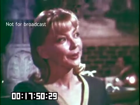 The still is from the educational film 'Immigrant Heritage,' featuring a woman speaking, likely in a dramatic or storytelling context. The scene is lit warmly, suggesting a thematic connection to cultural narratives, possibly relating to Irish heritage, as indicated by the involvement of the Irish Rovers. The film is marked 'Not for broadcast,' emphasizing its intended educational purpose rather than commercial distribution.