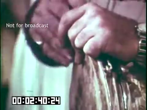 The still from 'Immigrant Heritage' features a close-up of hands engaged in a crafting activity, possibly related to traditional Irish heritage. The focus on the hands suggests a theme of craftsmanship or cultural expression. The image includes a timestamp and a 'Not for broadcast' label, indicating its use in a specific context such as education or preservation of cultural history.