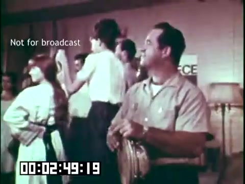 The still from 'Immigrant Heritage' features a group of people engaged in a lively performance, likely involving traditional Irish music and dance. In the foreground, a man holds a musical instrument, possibly a tambourine, while others in the background are dancing and enjoying the event. The scene conveys a sense of cultural celebration, reflecting the themes of heritage and community highlighted in the film. The text 'Not for broadcast' indicates it is a still intended for private use.