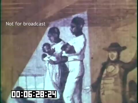 The still from 'Immigrant Heritage' features a historical mural or illustration depicting several children, likely of different ethnic backgrounds, holding small infants. Another figure, possibly an adult, stands nearby. The setting appears warm and illuminated, emphasizing themes of family and heritage. The frame is marked as 'Not for broadcast' and includes a timestamp indicating its position in the film.