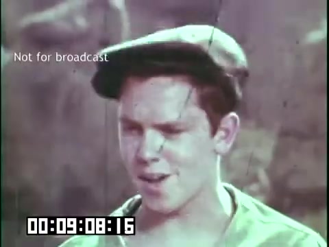 The still from 'Immigrant Heritage' features a young boy wearing a flat cap, appearing to engage in conversation or storytelling. His expression suggests a mix of seriousness and determination, set against a muted, natural background. The film's context relates to Irish culture and the immigrant experience, likely emphasizing themes of heritage and identity. The timestamp indicates it's approximately 9 minutes into the film, and there’s a note clarifying it’s not for broadcast.