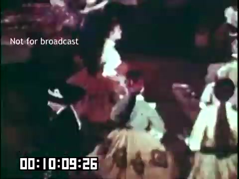 The still from 'Immigrant Heritage,' featuring the Irish Rovers, depicts a vibrant scene filled with dancers in traditional attire. The colors are rich and warm, highlighting the cultural expressions of the performers. The focus is on a group of individuals engaged in dance, capturing the essence of celebration and community heritage. A timestamp and a note indicating 'Not for broadcast' are visible at the bottom.