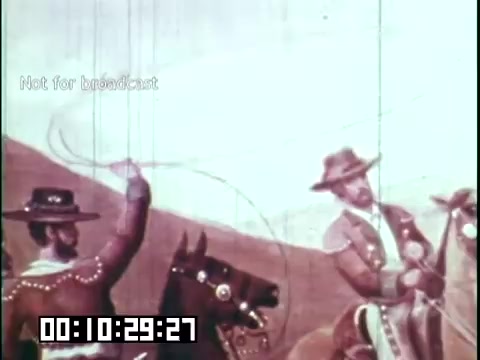 The still from 'Immigrant Heritage' depicts a scene featuring two riders on horseback, likely conveying themes of migration or cultural heritage. One rider is actively using a lasso, which suggests a Western or cowboy theme, while the landscape hints at an expansive terrain. The visual style appears vibrant, possibly indicating a cartoonish or animated treatment, characteristic of educational films aimed at illustrating historical narratives. The timestamp indicates this moment occurs 10 minutes and 29 seconds into the film.