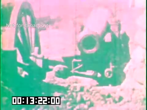 The still from 'Immigrant Heritage' shows a construction scene featuring a concrete mixer positioned on uneven terrain. The image has a vintage aesthetic, likely due to the 16mm film format, with pastel colors dominating the scene. A timer is displayed in the bottom left, indicating the specific point in the film. The context suggests it highlights aspects of immigrant labor and contributions to infrastructure, particularly reflecting on the Irish Rovers' heritage.