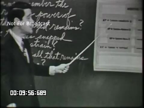 The still from 'Sixth Grade Linguistics' shows a male teacher standing in front of a blackboard, holding a pointer. He appears to be discussing linguistic concepts, indicated by the text and diagrams on the board. There are questions written in cursive and possibly a chart or table displayed next to him. The overall scene captures a classic educational setting typical of the mid-20th century.