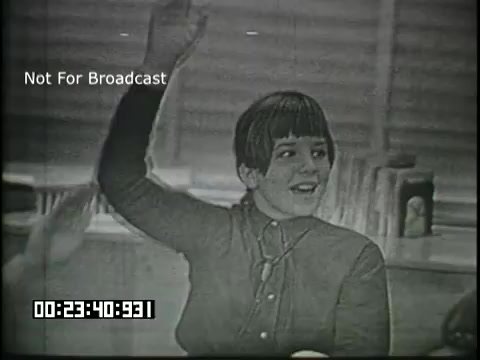 The still shows a young student in a classroom raising their hand, likely to answer a question or participate in a discussion. The student has short, styled hair and is wearing a button-up shirt. The background features classroom elements, suggesting a learning environment. The image comes from a 16mm educational film titled 'Sixth Grade Linguistics.' The text 'Not For Broadcast' indicates it is not intended for public airing.
