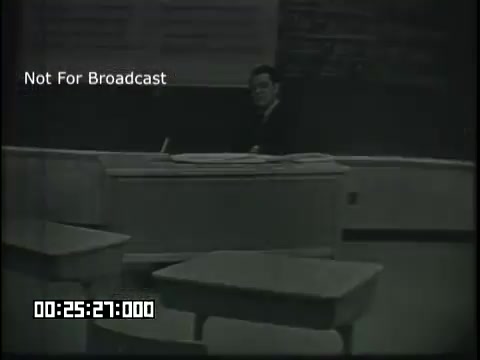 The still features a classroom setting with a teacher seated at a desk in front of a blackboard. The atmosphere appears educational, focusing on sixth-grade linguistics. The desks are arranged in front of the teacher, indicating a traditional classroom layout. The image has a vintage feel, typical of mid-20th century educational films.