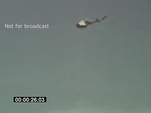 The still captures a Bell UH-1 Huey helicopter in flight against a cloudy sky. The helicopter is depicted in profile, showcasing its iconic shape and rotor blades. The footage is marked as 'Not for broadcast,' and a timestamp indicates a duration of 26 seconds. This segment is part of USAF helicopter training footage, likely highlighting maneuvers or operations involving the Huey.