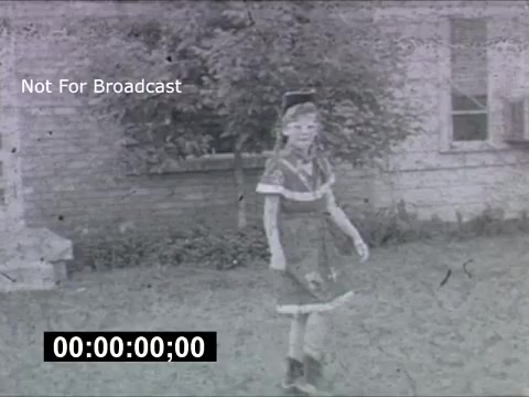The still appears to be from a 1950s home movie, featuring a young child dressed in a classic outfit with a hat, walking in a yard in front of a building. The image has a vintage feel with visible grain and slight discoloration typical of 16mm film. The text overlay indicates it's not for broadcast. There's a timer at the bottom showing the time code. The B-36 reference suggests a connection to aviation, likely highlighting a hidden or notable detail in the broader context of the footage.