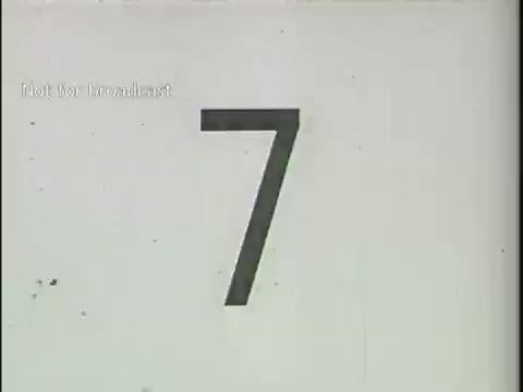 The still features a large, bold number '7' prominently displayed against a white background. It includes the label 'Not for Broadcast' in the upper left corner. This image is likely part of a countdown or sequence related to news footage, possibly indicating a segment or a transition to the next clip. The overall aesthetic is simplistic and utilitarian, typical of archival footage.