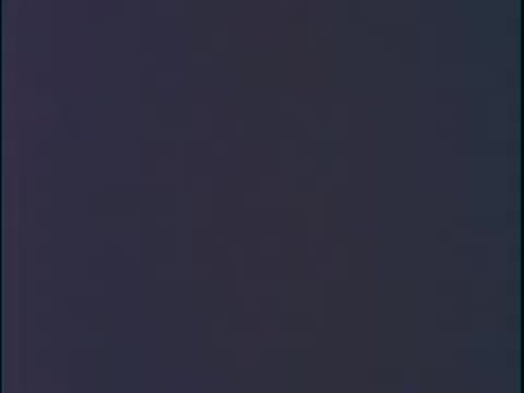 The still from the 'Unleaded Gas Info' film segment likely depicts a man discussing the benefits of unleaded gasoline. The speaker emphasizes that vehicles using this fuel experience significantly longer lifespans for mufflers, exhaust pipes, and spark plugs, attributing the improvements to reduced corrosion and deposits. The context suggests an informative presentation aimed at educating viewers about the advantages of unleaded gas introduced in the 1970s.