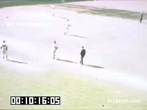 The still captures a scene from a Detroit Tigers game at Briggs Stadium, likely between 1948 and 1950. Players are seen on the field, with one umpire positioned near the infield. The grass appears well-maintained, while the surrounding area shows a bright, sunny atmosphere. The image is tinted with a vintage quality typical of Kodachrome film, offering a nostalgic glimpse into mid-20th-century baseball. A timecode at the bottom suggests it’s part of a longer segment. The overlay notes indicate it is not for broadcast.