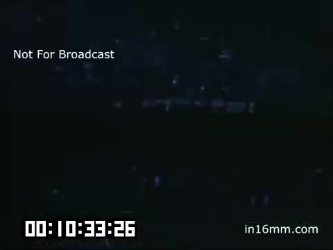 The still depicts a scene from Kodachrome footage of a Detroit Tigers game at Briggs Stadium, taken between 1948 and 1950. The image is dimly lit, suggesting night-time gameplay or low-light conditions. A timestamp is visible at the bottom, indicating the footage timeframe. Additionally, a watermark states 'Not For Broadcast,' indicating it is likely for archival or personal use. The atmosphere likely captures the historical essence of baseball during that era.