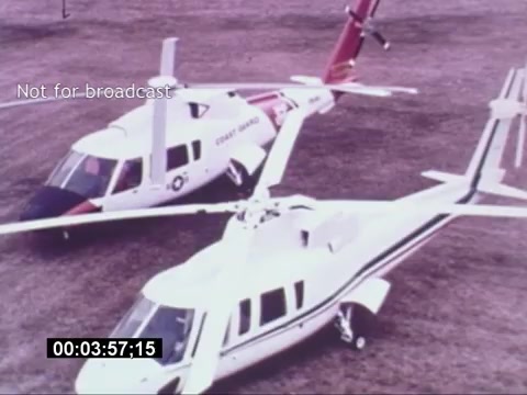 The still from the 'Sikorski S-76 Promotional Film' features two Sikorsky S-76 helicopters positioned on a grassy area. One helicopter is stylized in a white and green livery while the other sports a red accent with a 'Coast Guard' marking. The image captures a static display of the helicopters, emphasizing their design and capabilities, likely aimed at promoting their use in various operations. The timestamp at the bottom suggests this is part of a specific sequence within the film.