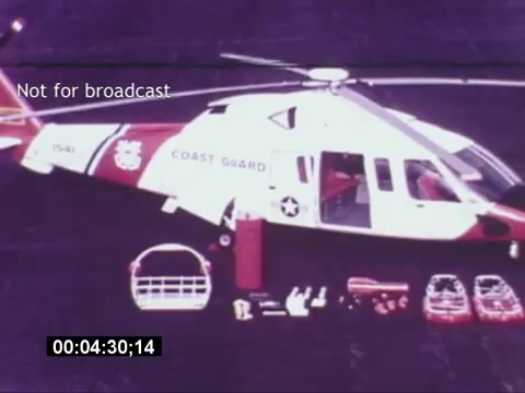 The still from the 'Sikorski S-76 Promotional Film' features a Sikorsky S-76 helicopter prominently displayed. The helicopter is painted in the distinctive colors of the Coast Guard, showcasing a red, white, and blue scheme. Various accessories are laid out beside the helicopter, possibly related to its operations or safety equipment. The image is marked 'Not for broadcast,' indicating it is for private viewing. The time code on the bottom suggests it comes from a specific segment of the film, but without audio, the context relies solely on the visuals.