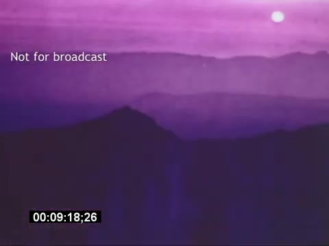 The still from the 'Sikorski S-76 Promotional Film' features a serene landscape bathed in a purple hue, suggesting either sunrise or sunset. The image captures distant mountains under a soft, glowing sky, with a sun partially visible. A timestamp in the corner marks the duration of the clip at 00:09:18:26, while the text 'Not for broadcast' indicates that this footage is intended for private or promotional use only. The lack of a soundtrack adds to the tranquil ambiance conveyed by the visuals.