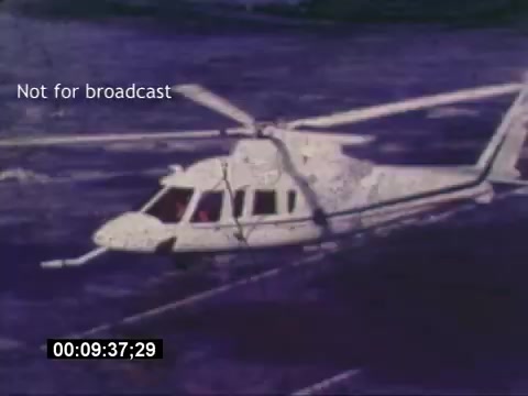 The still from the 'Sikorski S-76 Promotional Film' features a Sikorsky S-76 helicopter captured mid-flight over water. The helicopter is depicted in a side view, showcasing its sleek design and rotor blades in motion. The image has a distinct vintage quality, typical of 16mm film. A timestamp at the bottom indicates the footage duration, while a 'Not for broadcast' label signifies that this material is for private use only. The absence of sound adds a nostalgic touch to the viewing experience.