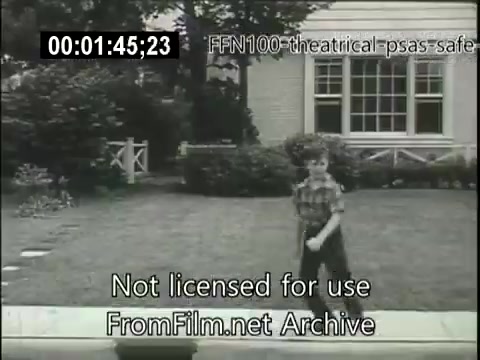 The still features a young boy in a plaid shirt walking in a yard, likely engaging in a playful activity. The background shows a house with a porch and a well-maintained lawn, reflecting a typical suburban setting of the late 1940s. This image is part of a series of public service announcements aimed at promoting safe driving practices, indicating a focus on community awareness and child safety.