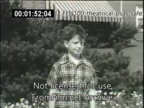 The still features a young boy standing outdoors, wearing a checkered shirt. He is likely part of a 1949 theatrical public service announcement promoting safe driving. The background includes greenery and a striped awning, emphasizing a suburban setting. The image conveys a nostalgic tone while aiming to raise awareness about road safety.