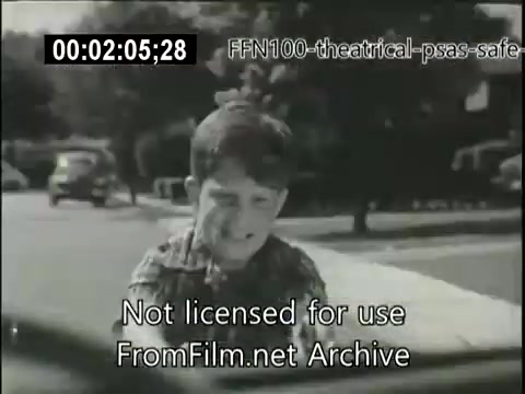 The still from the 1949 theatrical public service announcement features a young boy in a striped shirt, visibly concerned as he interacts with a vehicle. The background shows a suburban street with parked cars, emphasizing the message of safe driving. The film emphasizes awareness and caution around children, typical for safety campaigns of the time.