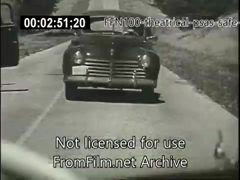 The still features a classic 1940s car driving on a rural road, likely part of a public service announcement emphasizing safe driving. The scene is monochrome, typical of the era, and accompanies a timestamp and archival watermark. The focus is on promoting road safety during a time when automobile use was rapidly increasing.