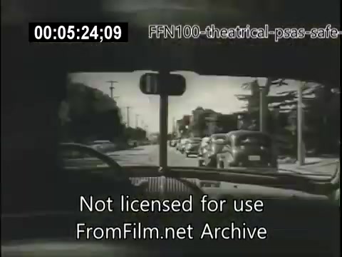 The still depicts a view from the interior of a car, looking out onto a street lined with parked vehicles. The image emphasizes safe driving practices, typical of public service announcements from 1949. The black-and-white footage reflects the era's style, focusing on road safety and awareness. The overlay indicates it is not licensed for use.