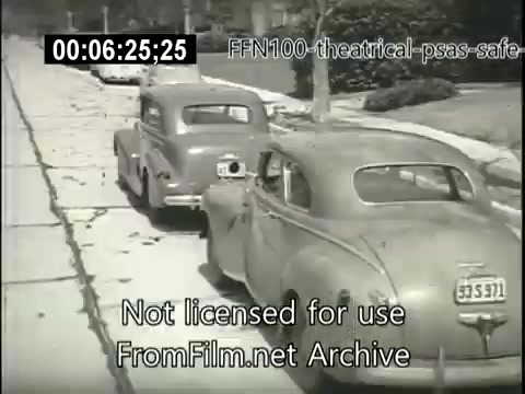The still depicts a black-and-white scene from a 1949 theatrical public service announcement focusing on safe driving. In the foreground, two vintage cars are parked by the side of a tree-lined street. The image emphasizes the importance of road safety and likely contains visuals aimed at reminding viewers to drive carefully. The overall tone reflects the aesthetic and societal values of the late 1940s.