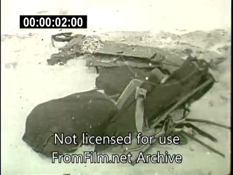 The still from 'Staten Island Plane Crash Aftermath - December 16th, 1960' depicts wreckage from the N6907C Lockheed Constellation following its mid-air collision. The image shows twisted and fragmented pieces of metal, indicating the severity of the crash. The ground is visible, suggesting this debris is situated in a recovery area. The film appears to be archival footage typical of that era, aimed at documenting the aftermath of the tragedy. The text overlay notes that the footage is not licensed for use.