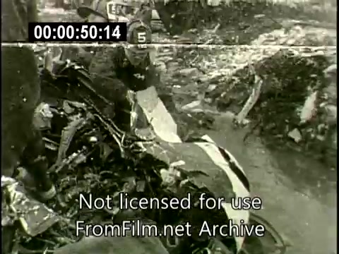 The still captures a scene from the aftermath of the N6907C Lockheed Constellation crash on December 16, 1960. It shows emergency responders examining the wreckage, amidst debris scattered across a snowy ground. The chaotic environment conveys the severity of the incident, highlighting both the destruction of the aircraft and the gravity of the mid-air collision with a DC plane. The image serves as a stark reminder of the tragic event and its impact.
