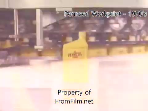 The still from the 'Pennzoil Factory/Refinery Workprint - 1980s' captures a moment from a 16mm negative, showcasing equipment in a refinery setting. The prominent yellow Pennzoil bottle stands out amidst the machinery, indicating the brand's operations. Debris can be seen in the film gate, hinting at the film's age and wear. The accompanying music from Underbelly adds an atmospheric layer, enhancing the nostalgic feel of the workprint.