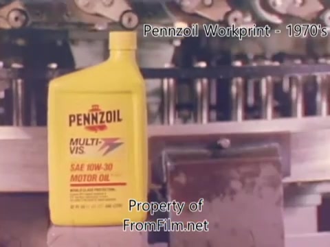 The still features a bottle of Pennzoil motor oil prominently displayed in a factory setting. The yellow bottle is labeled 'MULTI-VIS SAE 10W-30,' indicating its intended use. Behind it, machinery can be seen, suggesting an industrial environment typical of a refinery. The film is a workprint from the 1980s, capturing the essence of the time with some visible debris in the film gate, which adds to its vintage feel. Accompanying music from Underbelly enhances the atmosphere of the scene.