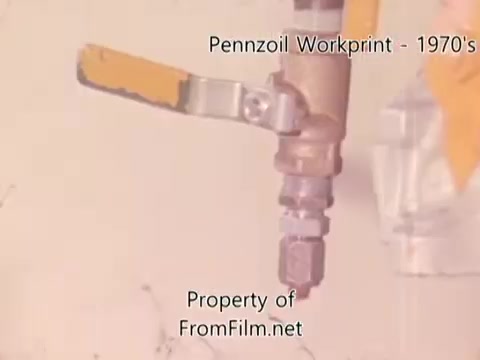 The still from the 'Pennzoil Factory⧸Refinery Workprint - 1980's' features equipment from a refinery, focusing on a valve or nozzle with a metal body and an orange handle. The image has a vintage quality, typical of 16mm film, and may show some debris within the film gate, which is not related to the projector. It's accompanied by music tracks from Underbelly, including 'I hear voices,' 'Asterism,' 'Italy Jr.,' and 'Land's End.'