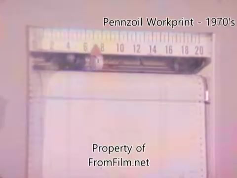 The still shows a 16mm film workprint from the Pennzoil factory or refinery from the 1980s. It features a film gate with a ruler above, indicating measurement. The film appears to have some debris, which is typical in workprints. The audio is provided by Underbelly, with tracks like 'I hear voices' and 'Asterism,' enhancing the visual content.