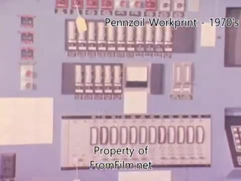 The 16mm still from 'Pennzoil Factory/Refinery Workprint - 1980's' features a control panel or machine operation area, presumably from a Pennzoil refinery. The panel includes various switches, buttons, and gauges, all set against a light blue background. There are some visible debris artifacts in the film, indicating prior usage on the projector. The accompanying music, by Underbelly, includes tracks like 'I Hear Voices' and 'Asterism.'