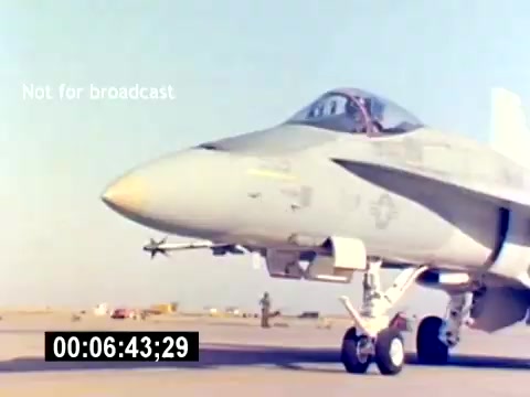 The still features a military fighter jet, likely an F/A-18 Hornet, positioned on an airfield. The aircraft is prominently displayed, showcasing its sleek, aerodynamic design and weaponry, including visible missiles. The background indicates a military environment, with other aircraft and personnel present. The overall tone conveys a sense of military prowess and recruitment for aviation ordnance roles within the USMC.