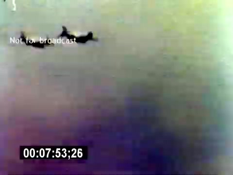 The still captures a scene from the 'USMC Aviation Ordnance Recruiting Film - Silent', showing silhouettes of two aircraft flying against a gradient-colored background. The image has a vintage aesthetic, typical of 16mm film, with muted colors and a slight blur. The timestamp indicates the specific moment in the film, and there is a watermark stating 'Not for broadcast.' The focus is on showcasing aviation, likely related to the U.S. Marine Corps' recruitment efforts.